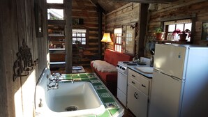 A rustic cabin kitchen with a wooden interior, a sink, stove, refrigerator, and a sofa. - Cozy, Rustic Cabins near Chico Hot Springs & only 35 mins to YELLOWSTONE PARK!! (Pray)