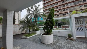 Une cour intérieure urbaine moderne, avec un sol carrelé, des plantes en pot et un immeuble à plusieurs étages en arrière-plan.