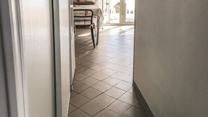 Un pasillo con suelo de baldosas, una mesa con mantel y una silla.