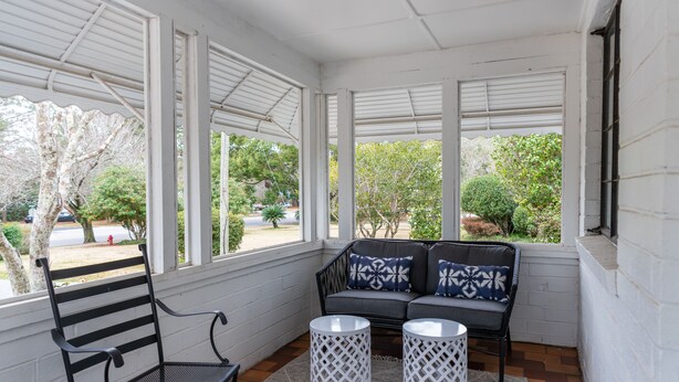 A covered porch with a bench, two white wicker tables, and a grey sofa with patterned cushions. - Palmetto Cottage - Historic 1925 cottage in Downtown Fairhope (Fairhope)