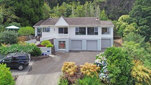 A two-story house with a white exterior, a garage, and a driveway. - Central Spacious Family House - Paihia House (Paihia)