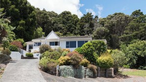 A single-story house with a white exterior, a front porch, and a driveway leading to the entrance. - Central Spacious Family House - Paihia House (Paihia)