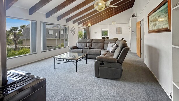 A spacious living room with a large sectional sofa, a glass coffee table, and a ceiling fan. - Central Spacious Family House - Paihia House (Paihia)