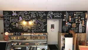 Een café met een krijtbord waarop gerechten staan vermeld, zoals 'Burger du Berger' en 'Entrecote'.