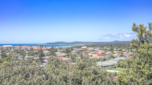 A coastal residential area with houses, a clear blue sky, and a view of the sea.