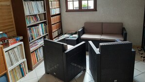 Um quarto com estante, sofá e janela.