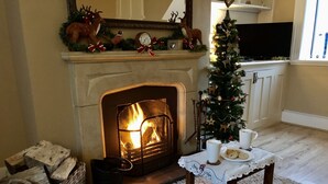 Una sala de estar acogedora con chimenea, un árbol de Navidad y una mesa con tazas y galletas.