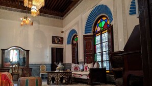 A traditional Moroccan interior with a patterned floor, wooden furniture, and a large window with stained glass. - firdaous palace of fes (Fes)
