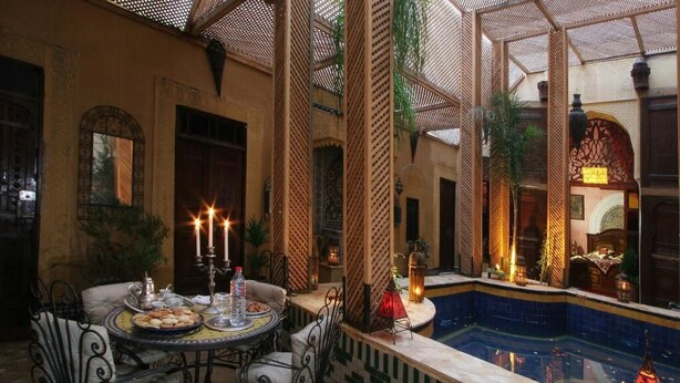 A dining area with a pool view, featuring a table set with candles, plates, and glasses. - firdaous palace of fes (Fes)