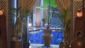 An ornate hallway with a large archway, patterned walls, and potted plants. - firdaous palace of fes (Fes)