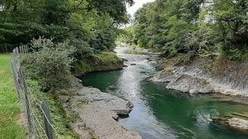 Un río serpentea por una zona boscosa con un sendero de piedra a lo largo de la orilla.