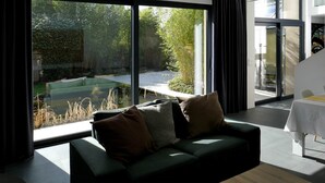 A modern living room with a large window, a sofa, and a dining area.