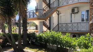 Un edificio de varios pisos con balcones, una palmera y un jardín bien cuidado.