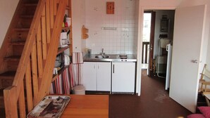 Uma cozinha com armários brancos, uma escada de madeira e um pequeno espaço de jantar.