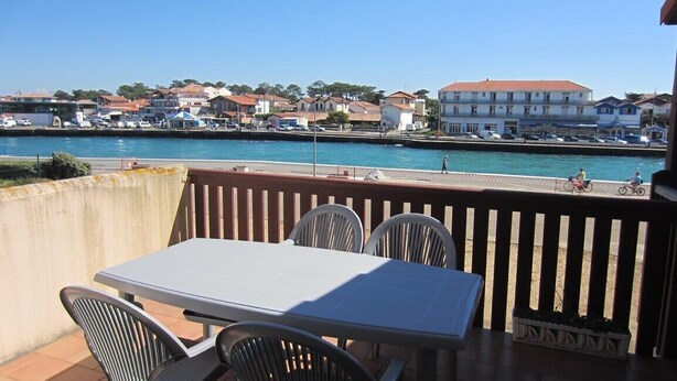 Terraço com mesa e cadeiras com vista para a frente marítima, com edifícios e barcos.