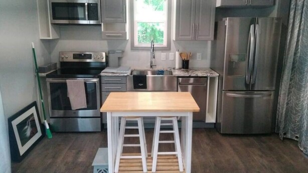 A compact kitchen with stainless steel appliances, a wooden table, and a window providing natural light. - WanderLost WanderLoft - Ideal for ATU grad student, visiting faculty, ANO outage (Dover)