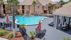 A pool area with lounge chairs and umbrellas, surrounded by a fence and potted plants. - 411  Near Disney Charming Spot! (Kissimmee)
