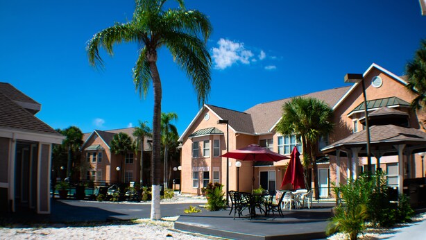 A hotel with a patio area featuring outdoor seating and palm trees. - 411  Near Disney Charming Spot! (Kissimmee)