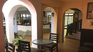 Un interior espacioso con una mesa redonda y sillas, una escalera y vistas al exterior.