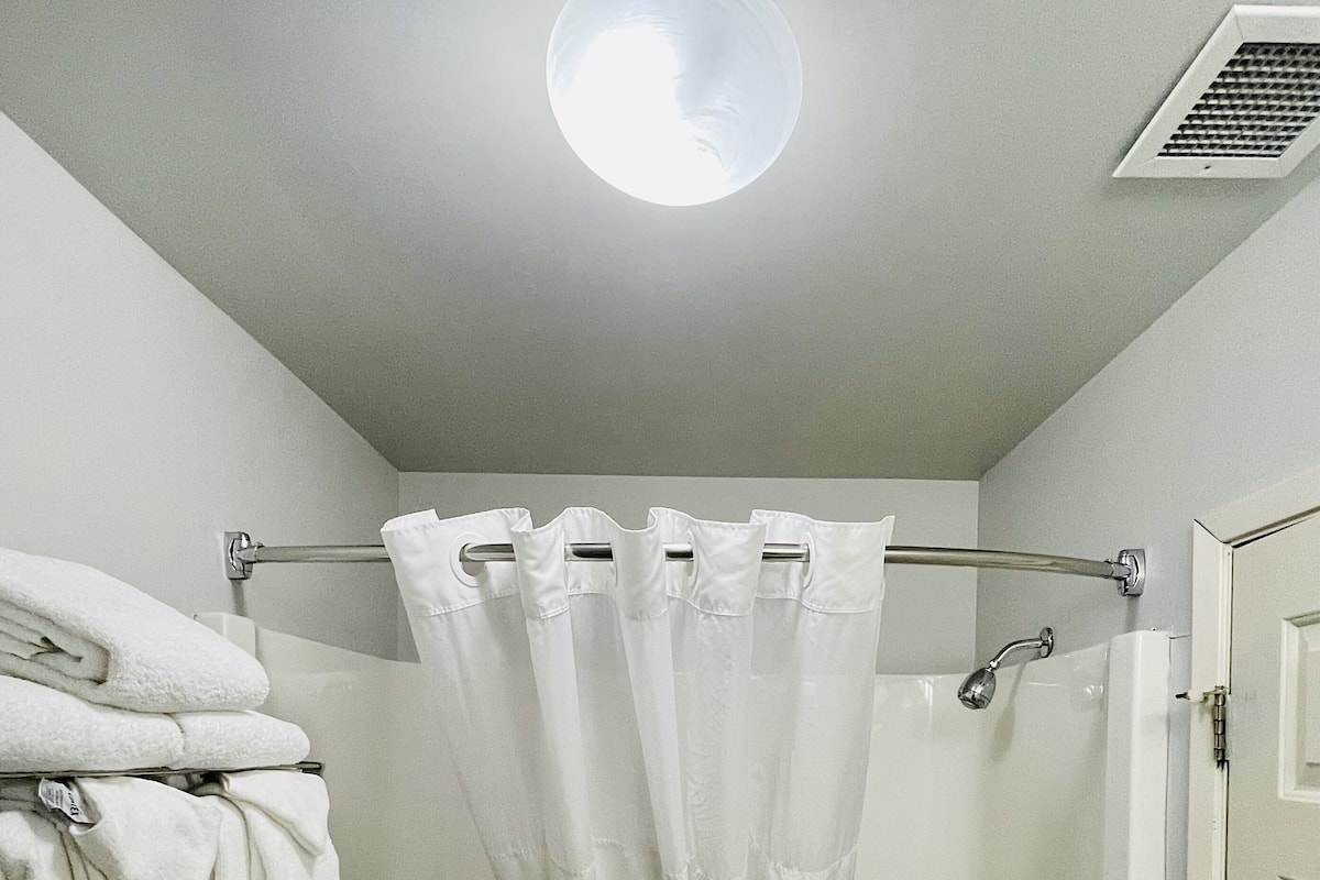 Ein Badezimmer mit Badewanne, Duschvorhang, Handtuchhalter und einer Tür.