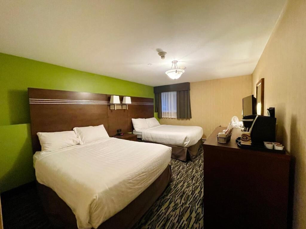 Une chambre d’hôtel avec deux lits, un bureau, un téléphone et un miroir.