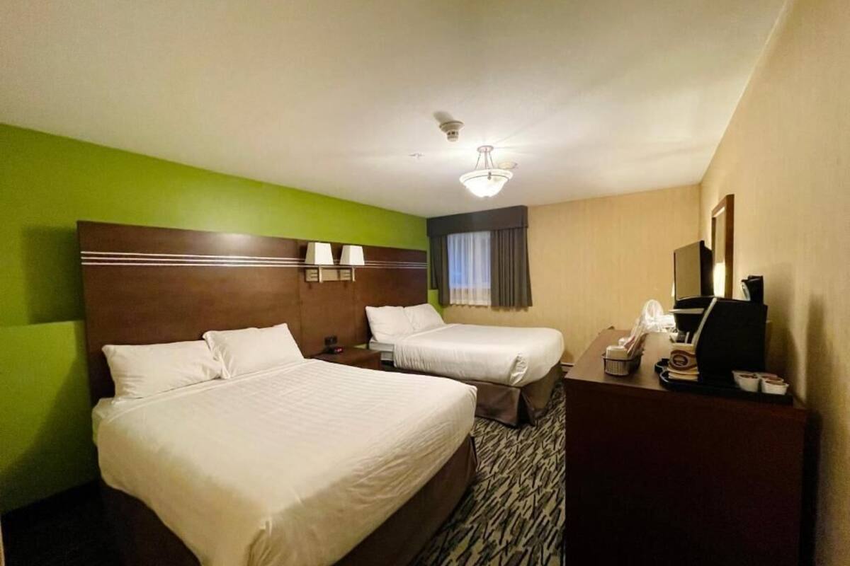 Ein Hotelzimmer mit zwei Betten, einem Schreibtisch, einem Telefon und einem Spiegel.