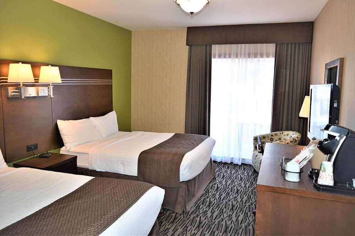 Ein Hotelzimmer mit zwei Betten, einem Schreibtisch mit Telefon und einem Stuhl.