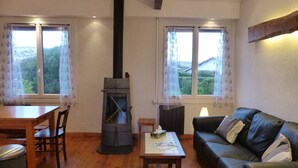 A cozy living room with a wood-burning stove, a dining table, and a leather sofa. - Apartment in villa "AIRE ONA" between lake and ocean for 4 people (Soorts-Hossegor)
