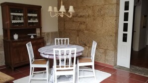 A dining area with a round table, white chairs, a wooden cabinet with glass doors, and a chandelier.