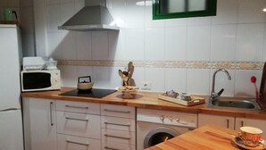 A compact kitchen with a refrigerator, microwave, sink, and a washing machine.