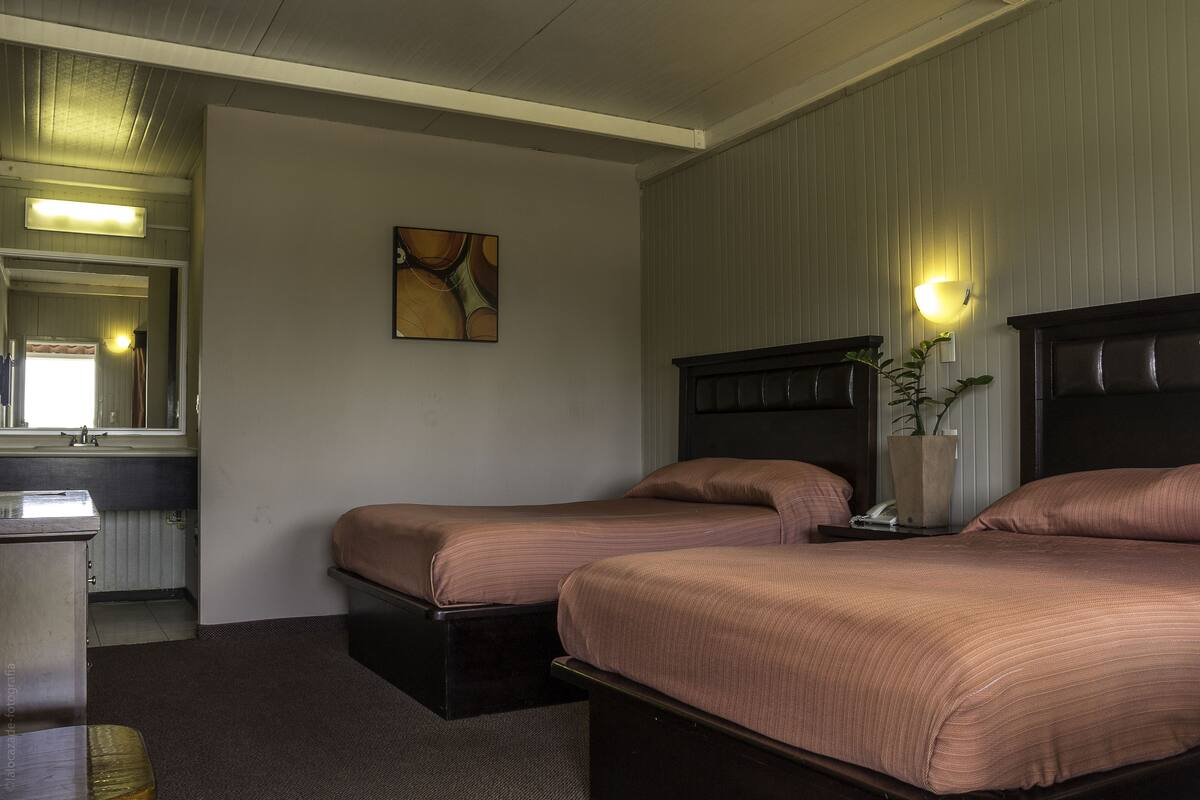 Ein Hotelzimmer mit zwei Betten, einem Schreibtisch, einem Spiegel und einer Wandleuchte.