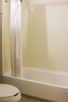 Un baño con bañera, inodoro y cortina.