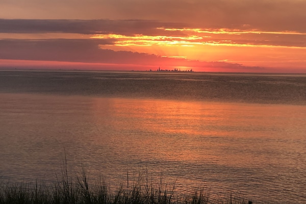 Views of the Chicago skyline across the lake while the sun sets.