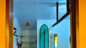 Una habitació amb un llit, una taula de surf i una finestra amb vista al mar.