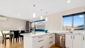 Een moderne keuken met witte kasten, een vaatwasser en hangende lampen.
