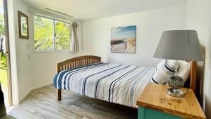 Una camera da letto con un letto, una lampada da comodino, un quadro appeso e una finestra con tende.