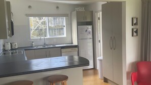 Una cucina moderna con isola centrale, due sgabelli di legno, un frigorifero e una finestra vista alberi.