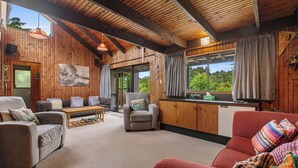 Un salón acogedor con paredes de madera, un sofá, un sillón rojo y una mesa de centro.