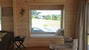 Een gezellig interieur van een chalet met houten details, een vensterbank met kussens, een kleine tafel en een bord aan de muur.