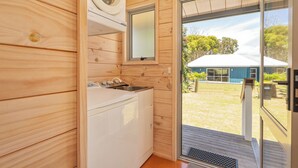 Een kleine keuken met een wasmachine, een spoelbak en een raam met uitzicht op een huis.
