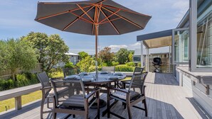 Een terras met een ronde tafel, stoelen en een grote parasol.