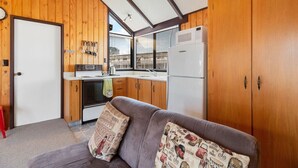 A compact kitchen with wooden cabinets, a refrigerator, and a stove.