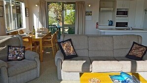Una sala de estar con un sofá, dos sillones, una mesita de centro y una zona comedor con una mesa y sillas.