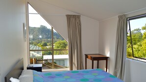 Un dormitorio con una cama, una mesita de noche, una pequeña mesa y una ventana con cortinas.