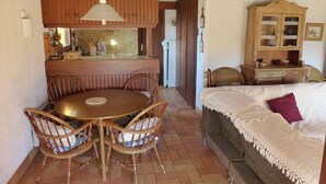 A cozy kitchen with wooden cabinets, a dining table with chairs, and a sofa with a blanket. - The "Maison des Moineaux" between lake and ocean for 6 persons (Soorts-Hossegor)