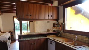 A compact kitchen with wooden cabinets, a dishwasher, and a window with a view. - The "Maison des Moineaux" between lake and ocean for 6 persons (Soorts-Hossegor)