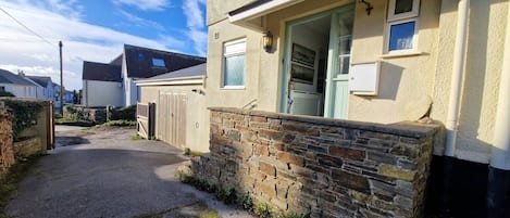 A residential property with a stone wall, a wooden gate, and a clear sky.