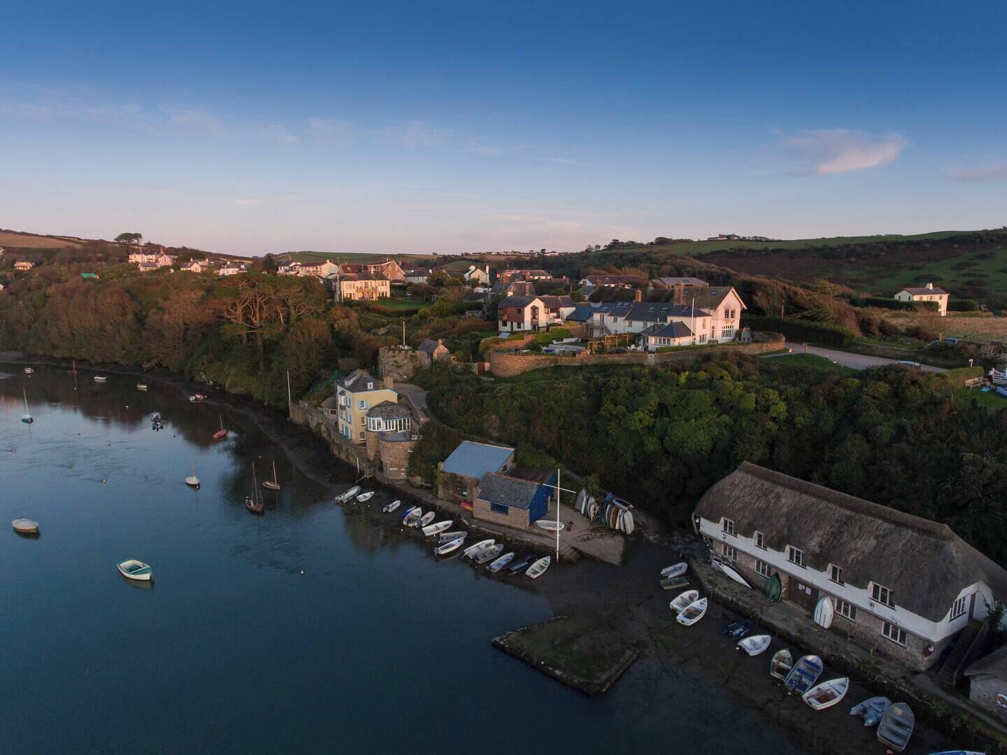 Uma vila costeira com um porto de recreio, casas e um edifício imponente com telhado de palha.