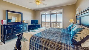 Ein Schlafzimmer mit einem großen Bett, einem Schminktisch, einem Fernseher und einem Balkon mit Blick.