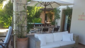 A covered outdoor seating area with a wicker sofa, chairs, and a pool table. - Luxurious 3 bedroom villa with private pool garden and sea view (Kouklia)
